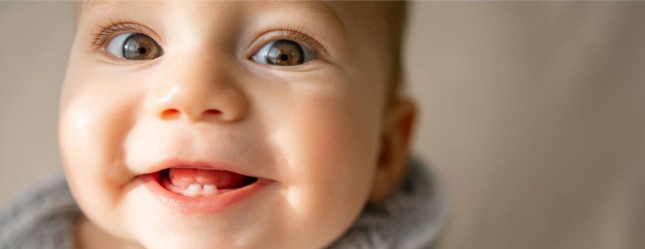 A child wearing a gray scarf, looking slightly to the side. The background is blurred.